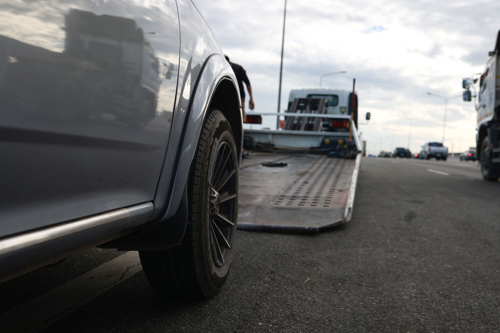 Loading a car onto a tow truck. A broken-down vehicle on the highway receives expert care from a tow truck, getting back on track for a safe and hassle-free journey.